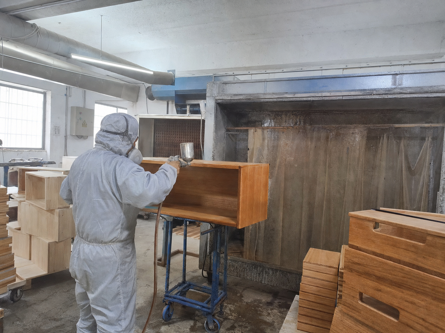 Worker spray-finishing a wooden box