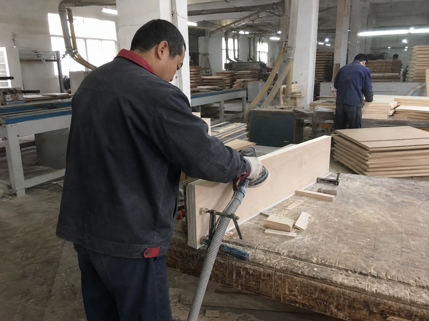 Worker fine-sanding a wooden product